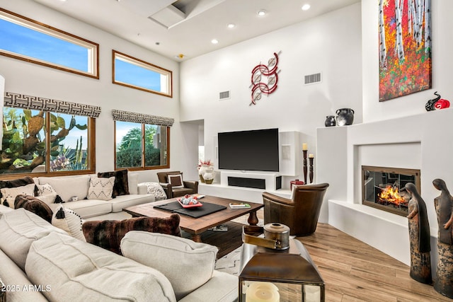 living room featuring light wood-type flooring and a towering ceiling