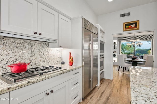 kitchen featuring extractor fan, decorative backsplash, white cabinetry, and stainless steel appliances