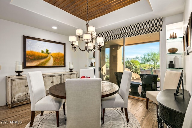 dining area featuring hardwood / wood-style floors, a chandelier, a raised ceiling, and wood ceiling