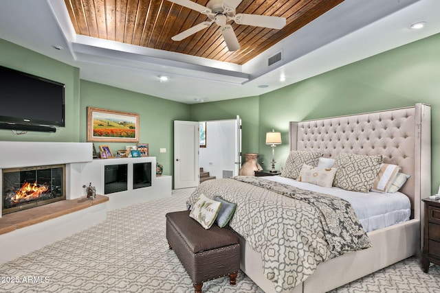 bedroom featuring a fireplace, wooden ceiling, and ceiling fan