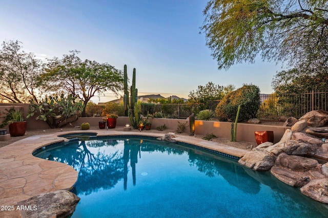 pool at dusk with an in ground hot tub