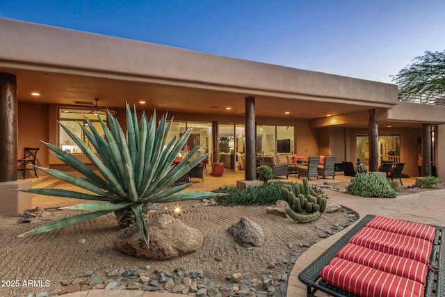 back house at dusk with an outdoor living space, a patio area, and ceiling fan