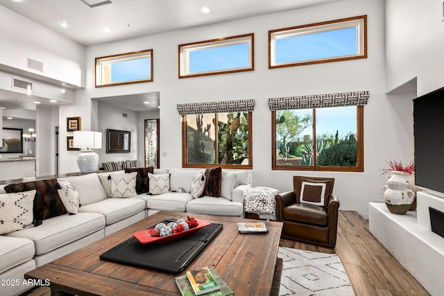 living room featuring a high ceiling, a wealth of natural light, and light wood-type flooring