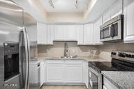 kitchen with light stone counters, white cabinetry, sink, and appliances with stainless steel finishes