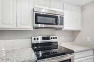 kitchen with white cabinets, range, and light stone counters