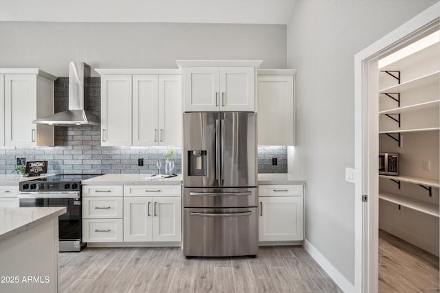 kitchen with wall chimney range hood, electric range, stainless steel refrigerator with ice dispenser, light stone countertops, and white cabinets