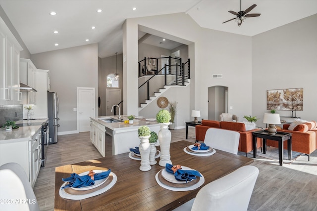 dining room with ceiling fan, sink, high vaulted ceiling, and light hardwood / wood-style floors