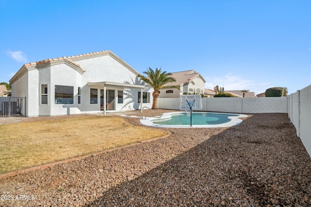 rear view of property featuring central AC unit, a fenced in pool, a patio area, and a lawn