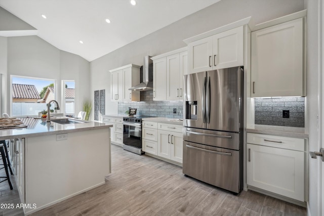 kitchen with sink, appliances with stainless steel finishes, white cabinetry, an island with sink, and wall chimney exhaust hood