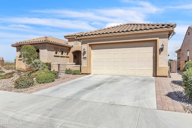 mediterranean / spanish-style house with an attached garage, fence, driveway, a tiled roof, and stucco siding