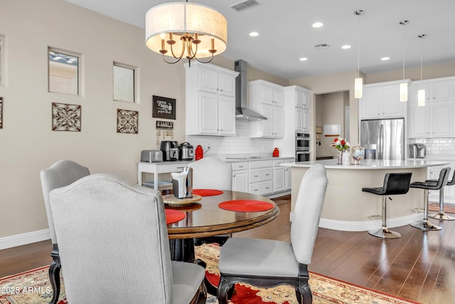 dining area with dark wood-type flooring, visible vents, a notable chandelier, and baseboards