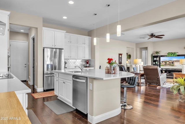 kitchen with stainless steel appliances, open floor plan, a sink, and dark wood-style floors