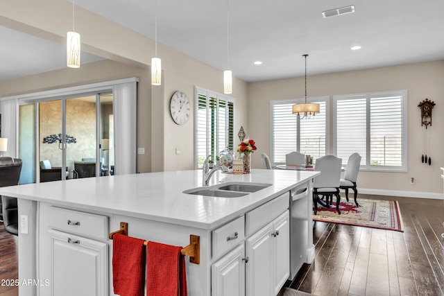 kitchen with dark wood finished floors, visible vents, stainless steel dishwasher, white cabinets, and a sink