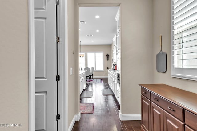 corridor with dark wood-style floors, visible vents, baseboards, and recessed lighting