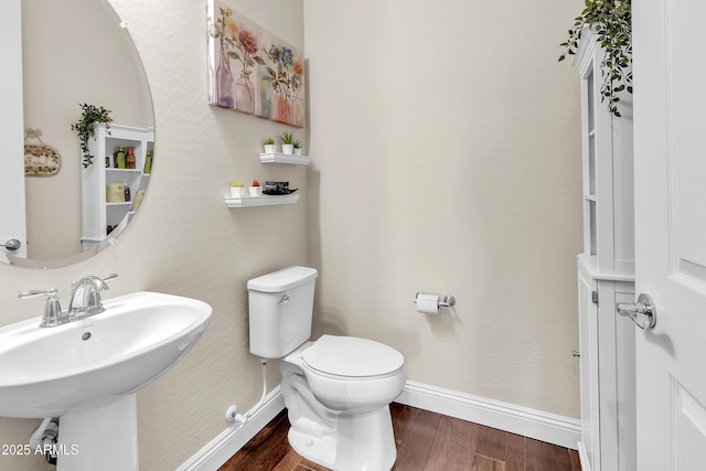 bathroom with baseboards, a sink, toilet, and wood finished floors