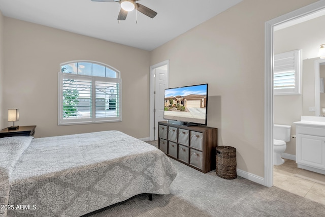 bedroom with ensuite bath, baseboards, ceiling fan, and light colored carpet