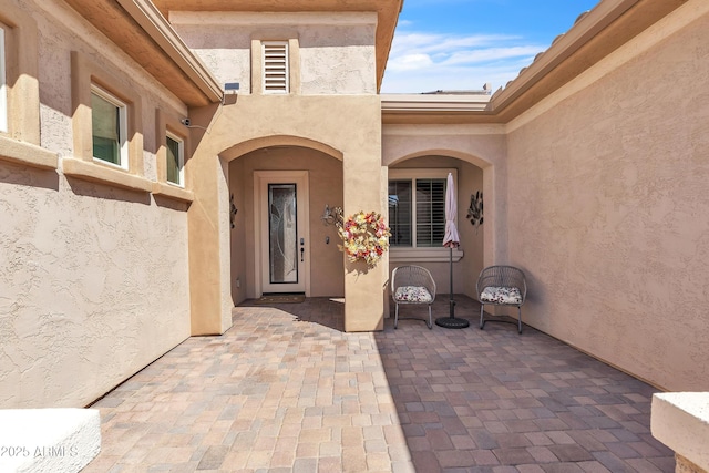 entrance to property with a patio area and stucco siding