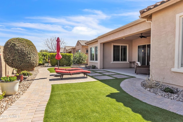 view of yard featuring ceiling fan and a patio