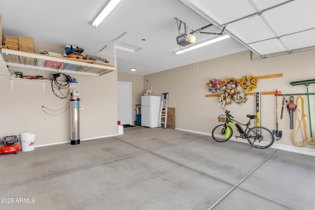 garage featuring baseboards, a garage door opener, and freestanding refrigerator