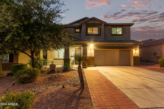 traditional home with covered porch, stucco siding, an attached garage, and driveway