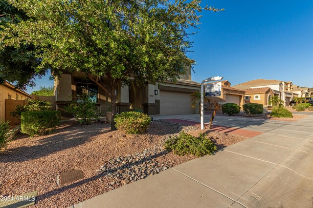 view of front of property featuring stucco siding, fence, a residential view, concrete driveway, and a garage