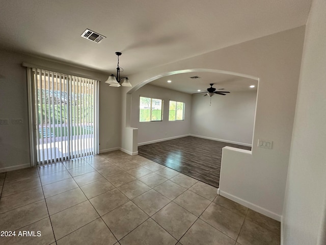 empty room with ceiling fan with notable chandelier and light hardwood / wood-style flooring