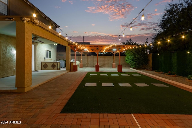 yard at dusk featuring exterior kitchen, a fenced backyard, and a patio