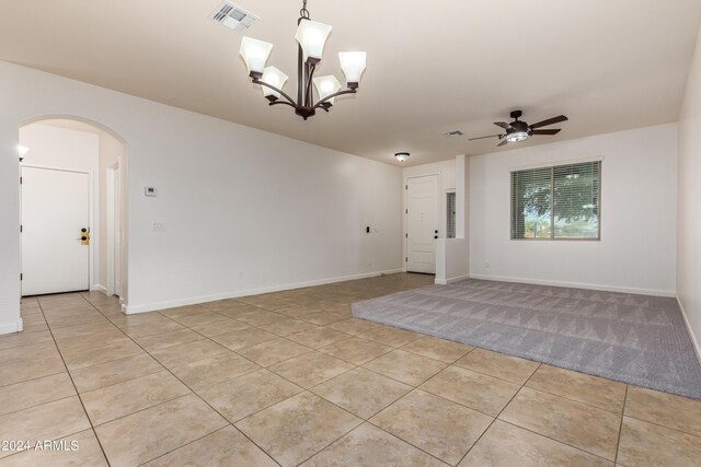 empty room with light tile patterned floors, visible vents, arched walkways, and ceiling fan with notable chandelier