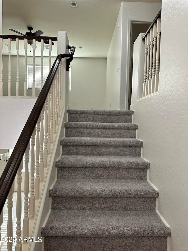 staircase featuring ceiling fan