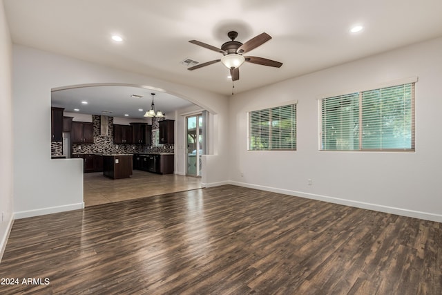 unfurnished living room with arched walkways, visible vents, baseboards, and wood finished floors