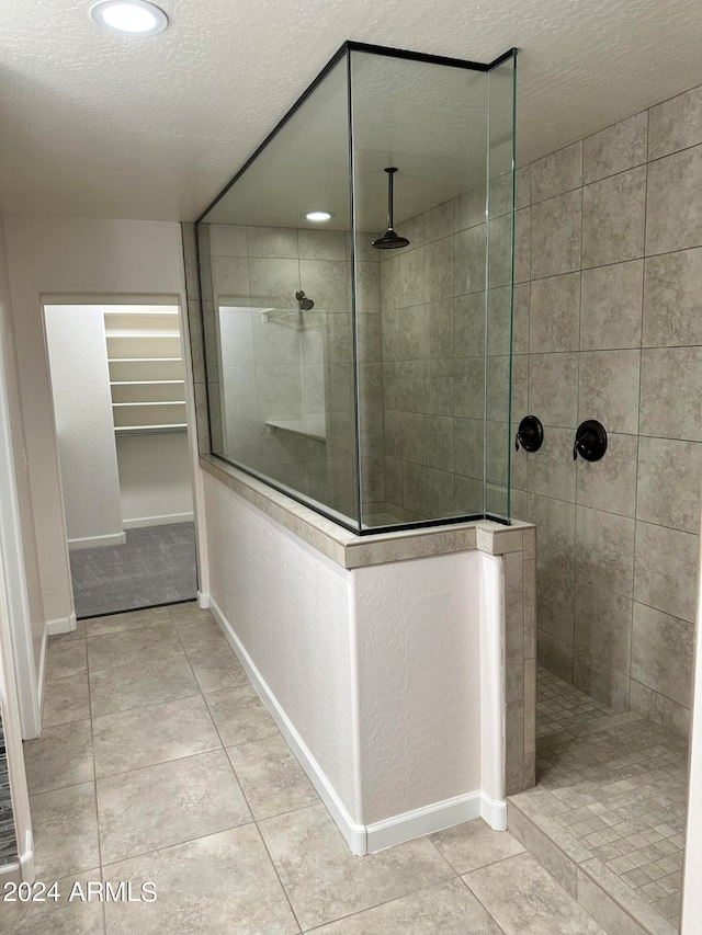 bathroom with tile patterned floors, a tile shower, and a textured ceiling