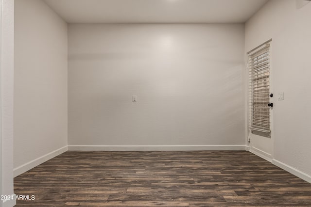 unfurnished room with baseboards and dark wood-style floors