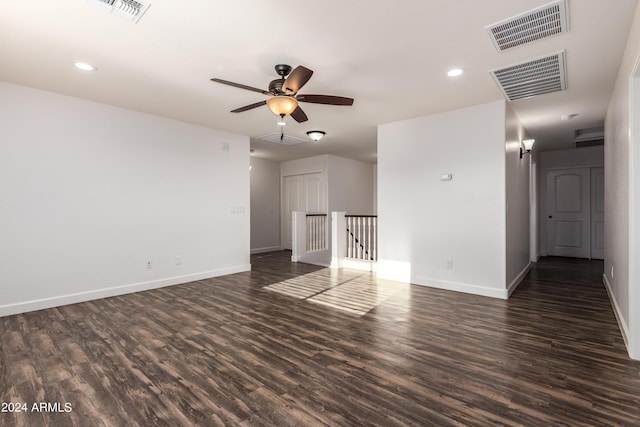 empty room featuring visible vents, baseboards, and dark wood-type flooring