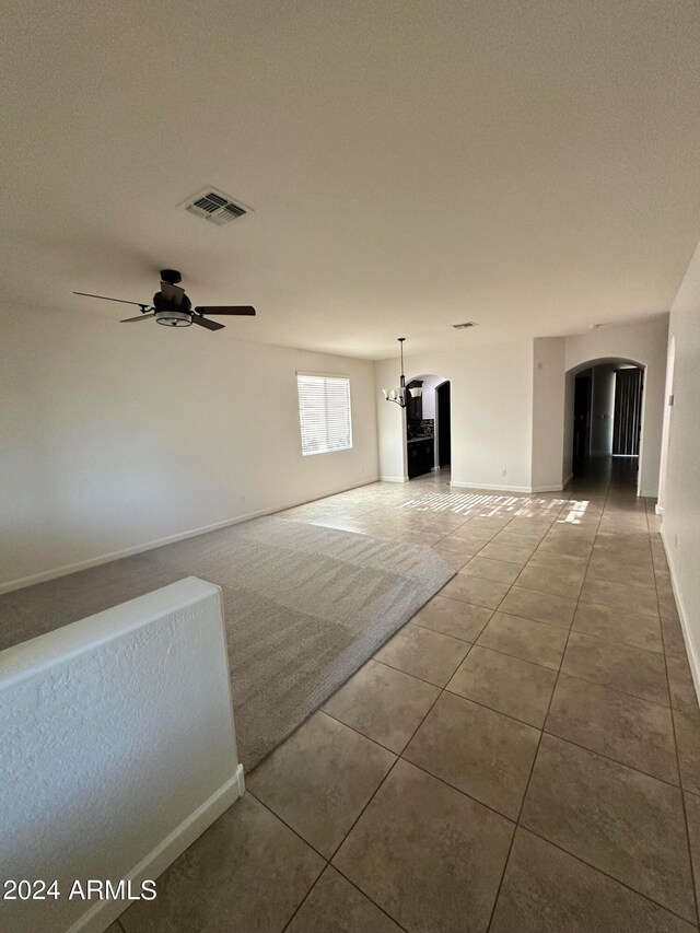 spare room with a textured ceiling, ceiling fan with notable chandelier, and tile patterned floors