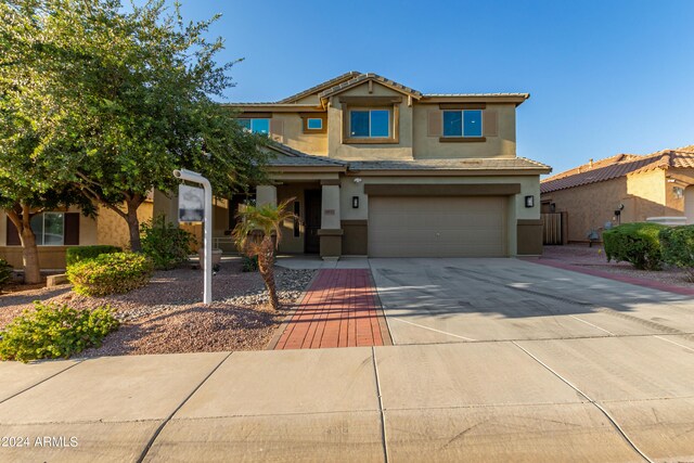 view of front of property with a tiled roof, a garage, driveway, and stucco siding