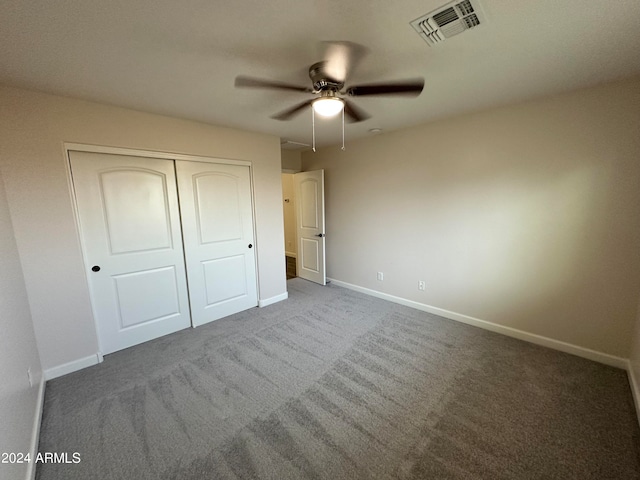 unfurnished bedroom with dark colored carpet, ceiling fan, and a closet