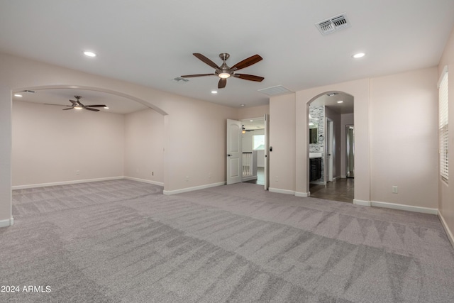 empty room featuring arched walkways, carpet flooring, recessed lighting, and visible vents