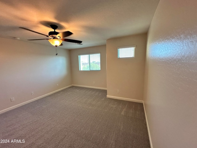 empty room featuring ceiling fan and dark carpet