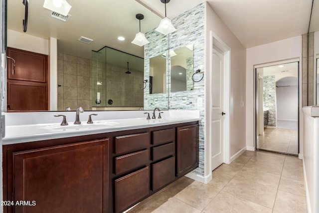 bathroom with tile patterned flooring, visible vents, tiled shower, and a sink