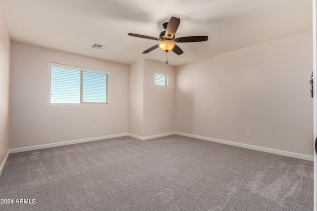 carpeted spare room with visible vents, ceiling fan, and baseboards