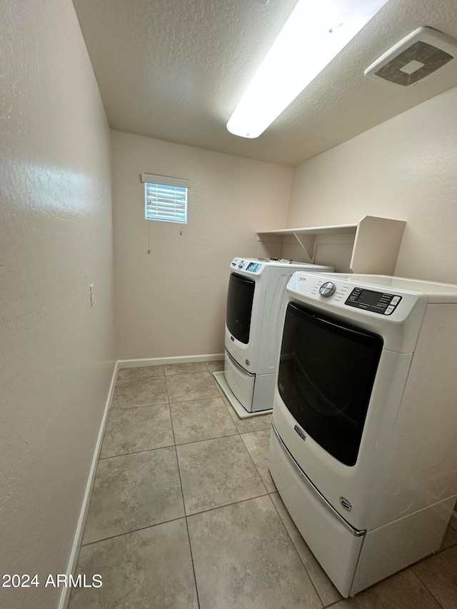 washroom featuring independent washer and dryer, a textured ceiling, and light tile patterned floors