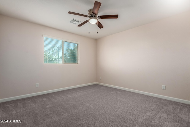 empty room with visible vents, carpet flooring, a ceiling fan, and baseboards