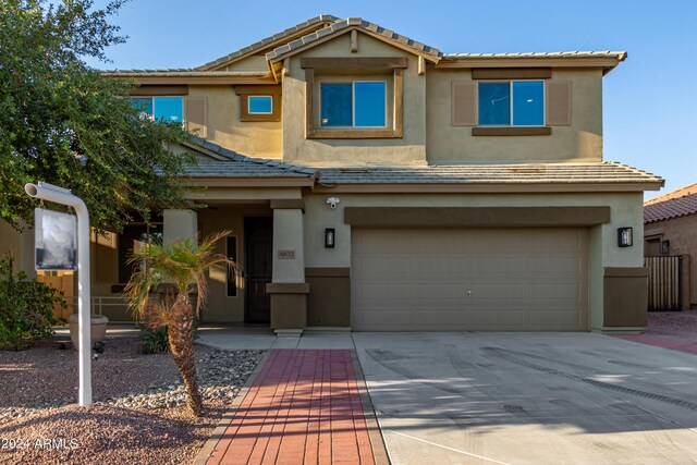 view of front of property with stucco siding, driveway, a tile roof, and a garage