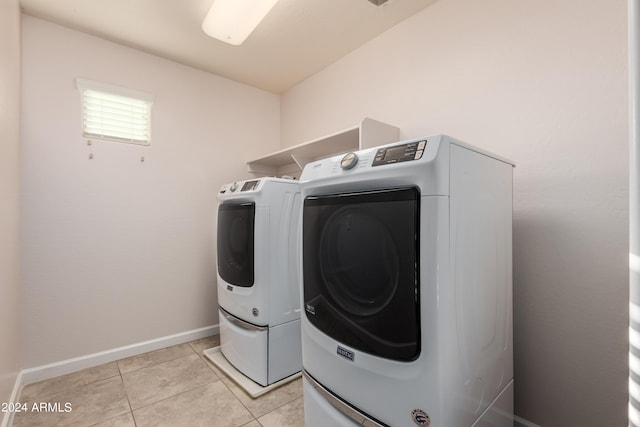 washroom featuring washer and clothes dryer, laundry area, baseboards, and light tile patterned floors