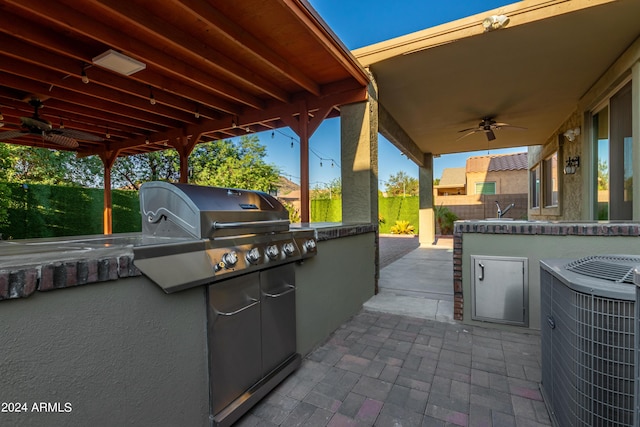 view of patio / terrace with a sink, a ceiling fan, central AC, and an outdoor kitchen