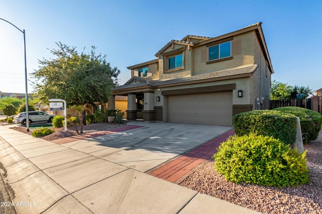 view of front facade with stucco siding, driveway, a tile roof, fence, and an attached garage