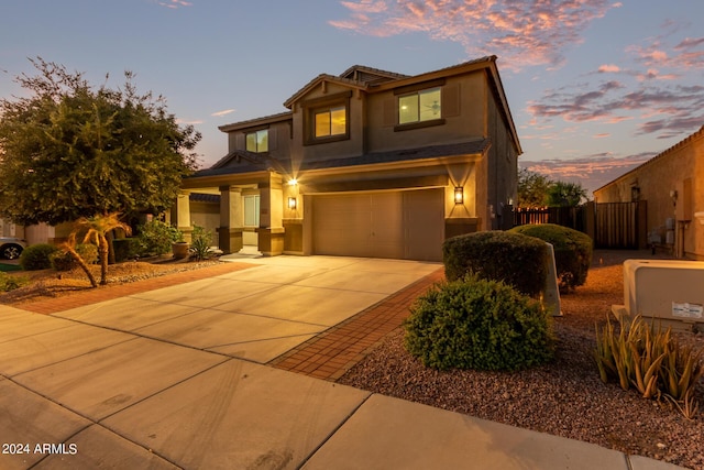 view of front of home with stucco siding, concrete driveway, an attached garage, and fence