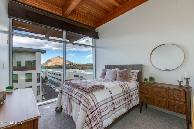 bedroom with wood ceiling, carpet flooring, beam ceiling, a mountain view, and a wall of windows