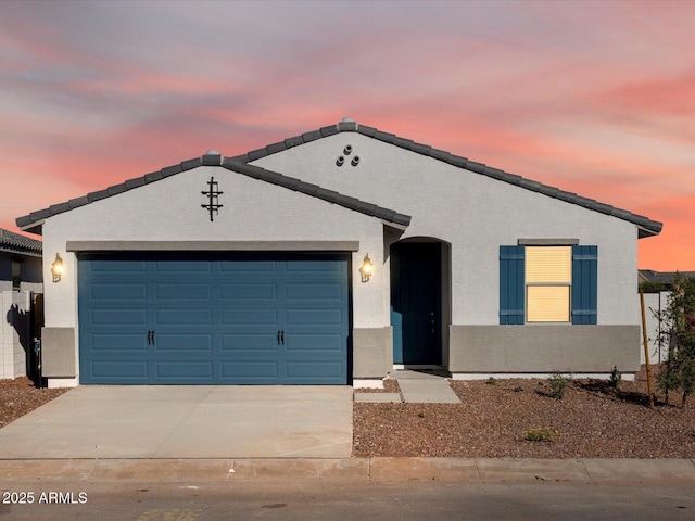 ranch-style home with stucco siding, an attached garage, and driveway