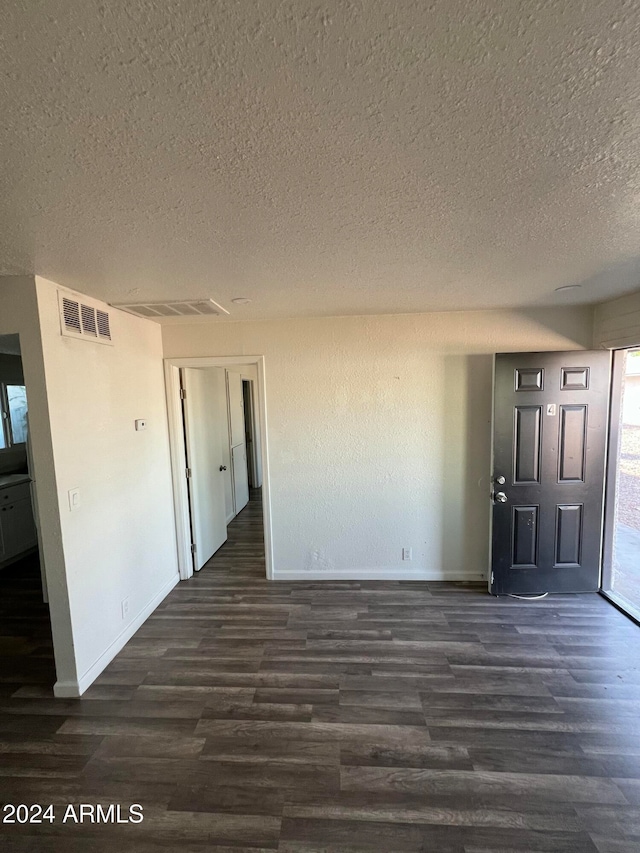 unfurnished room featuring dark wood-type flooring and a textured ceiling